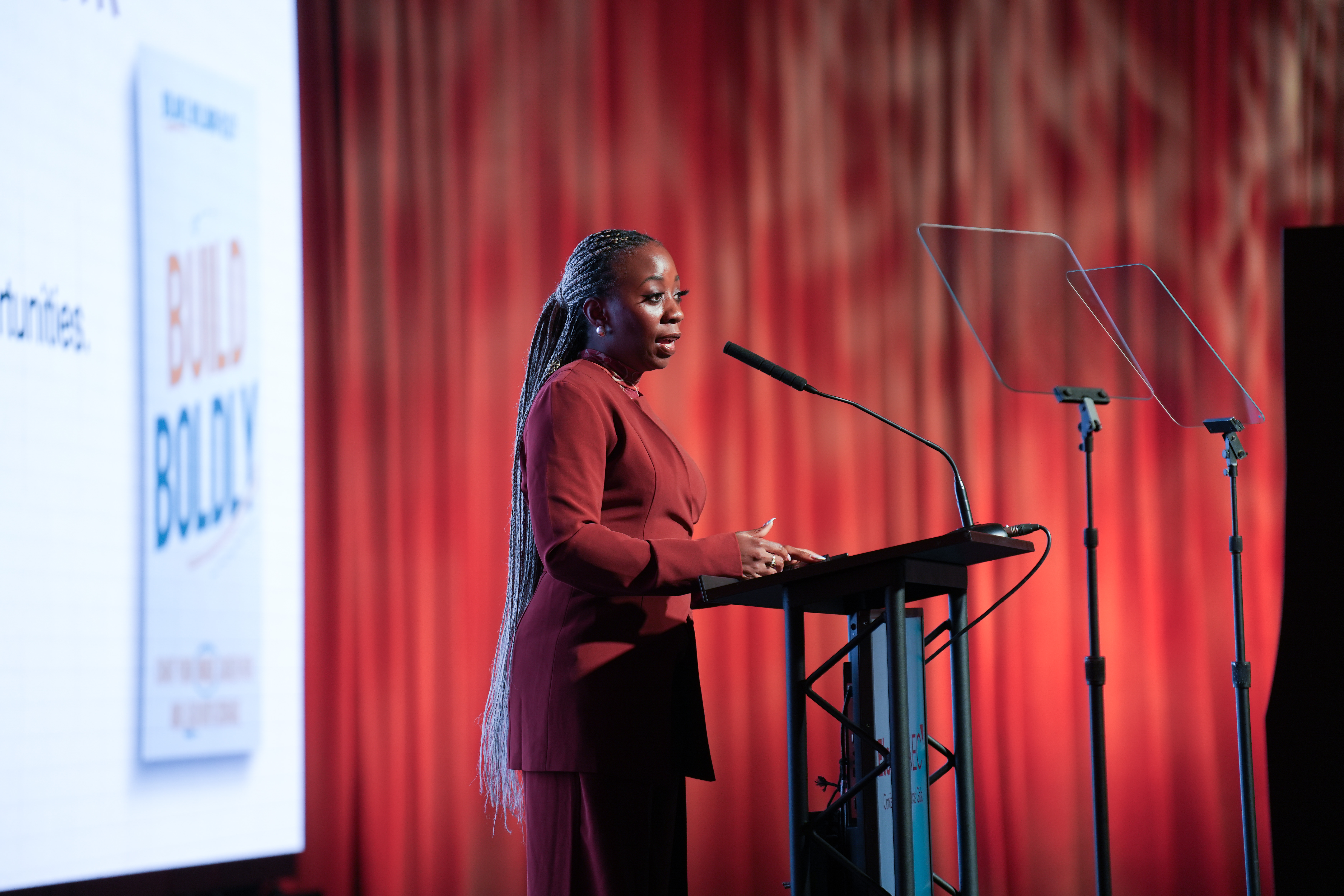 Bolanle Williams-Olley on stage with Build Boldly on screen